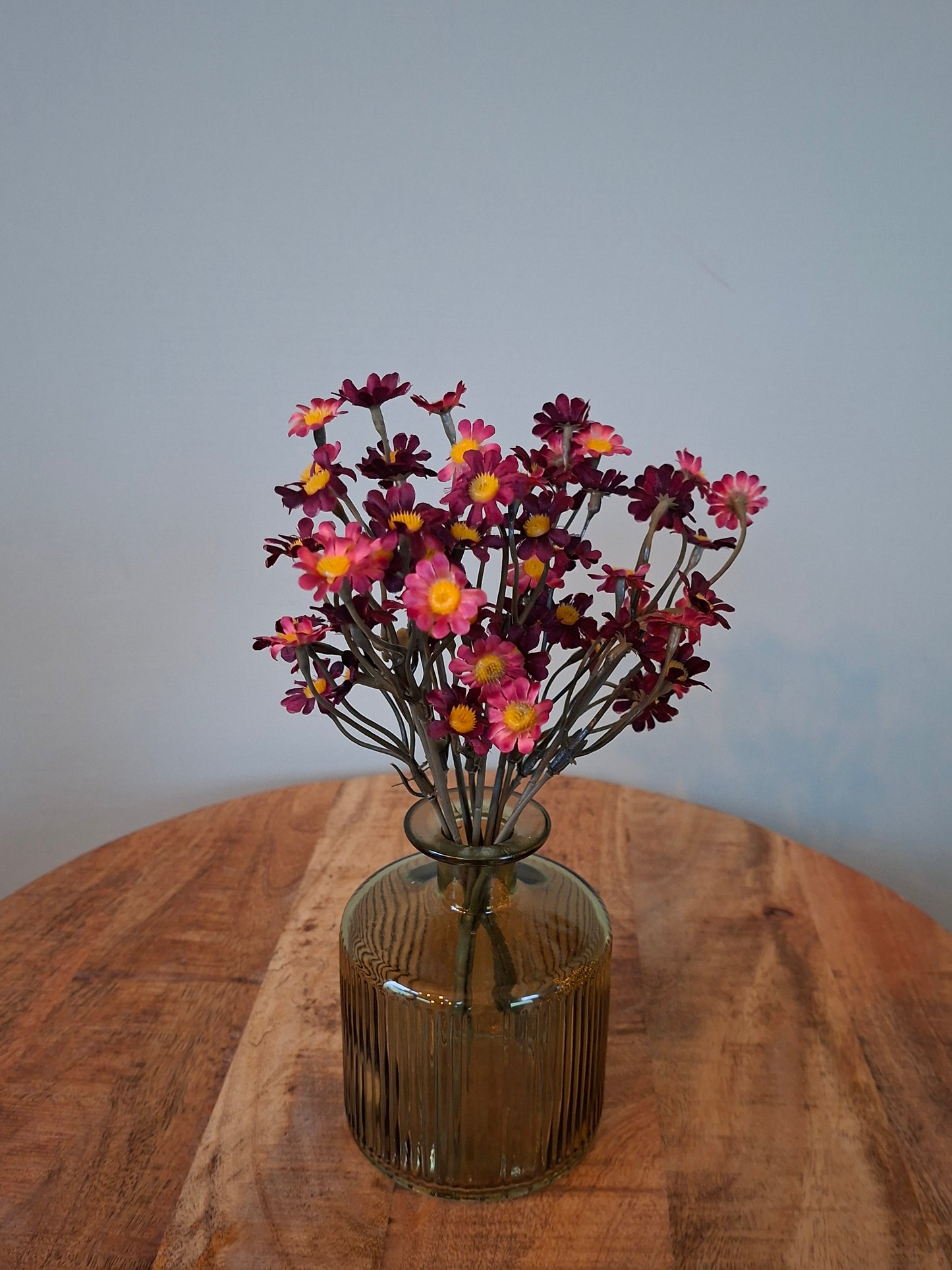 Klein groen vaasje met donkerrode margrietjes – stijlvol en sfeervol woonaccent
