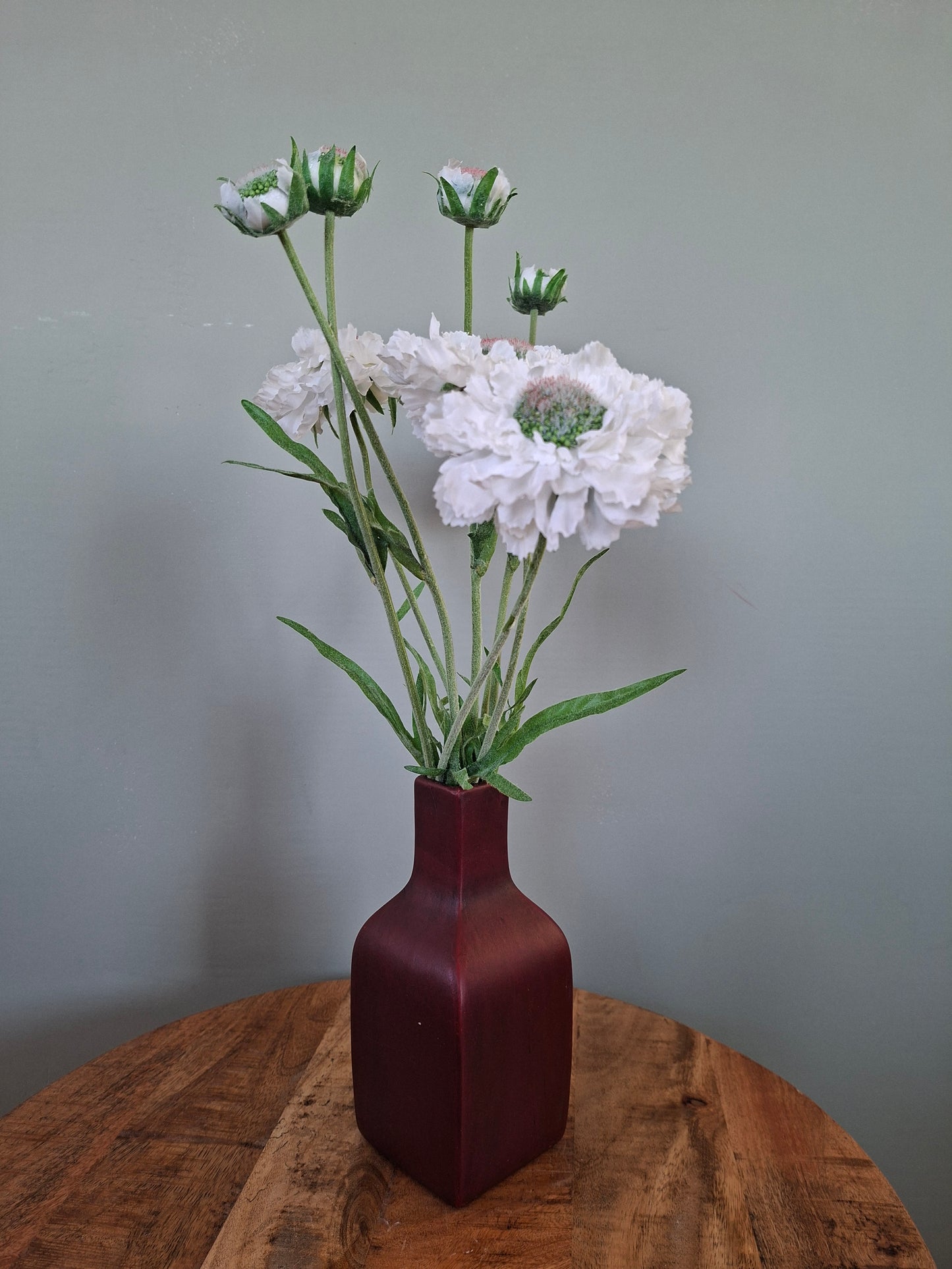 Donkerrode keramieken vaas met witte bloemen – elegant en sfeervol woonaccent