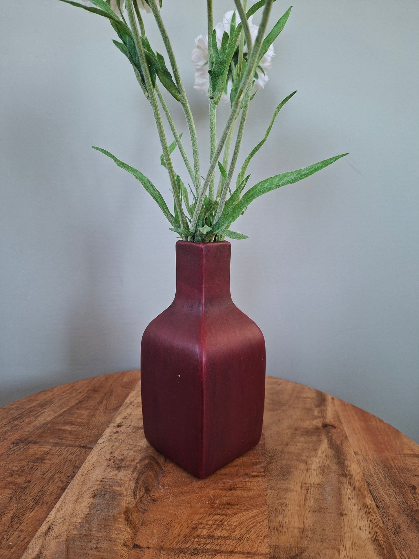 Donkerrode keramieken vaas met witte bloemen – elegant en sfeervol woonaccent