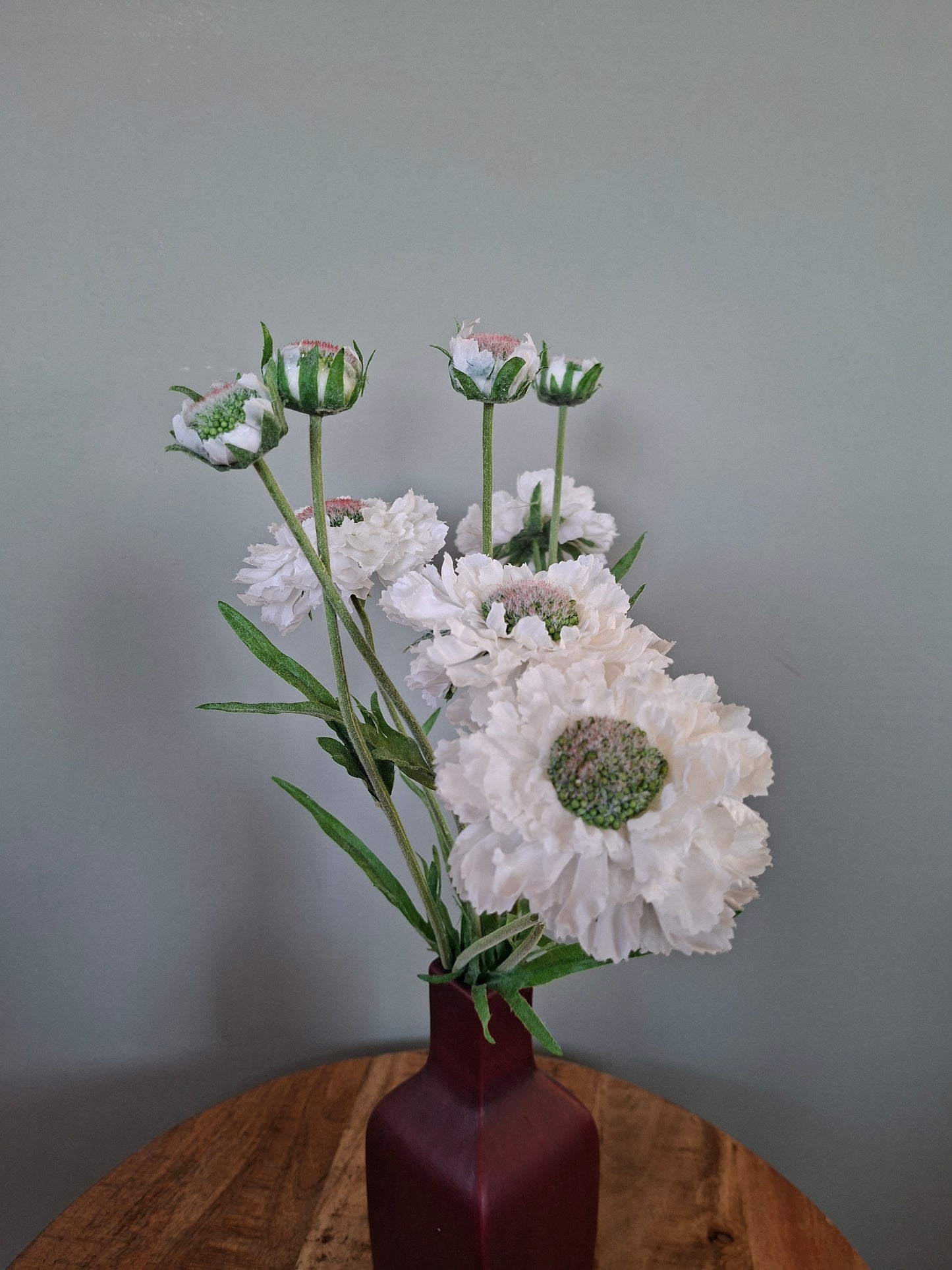 Donkerrode keramieken vaas met witte bloemen – elegant en sfeervol woonaccent